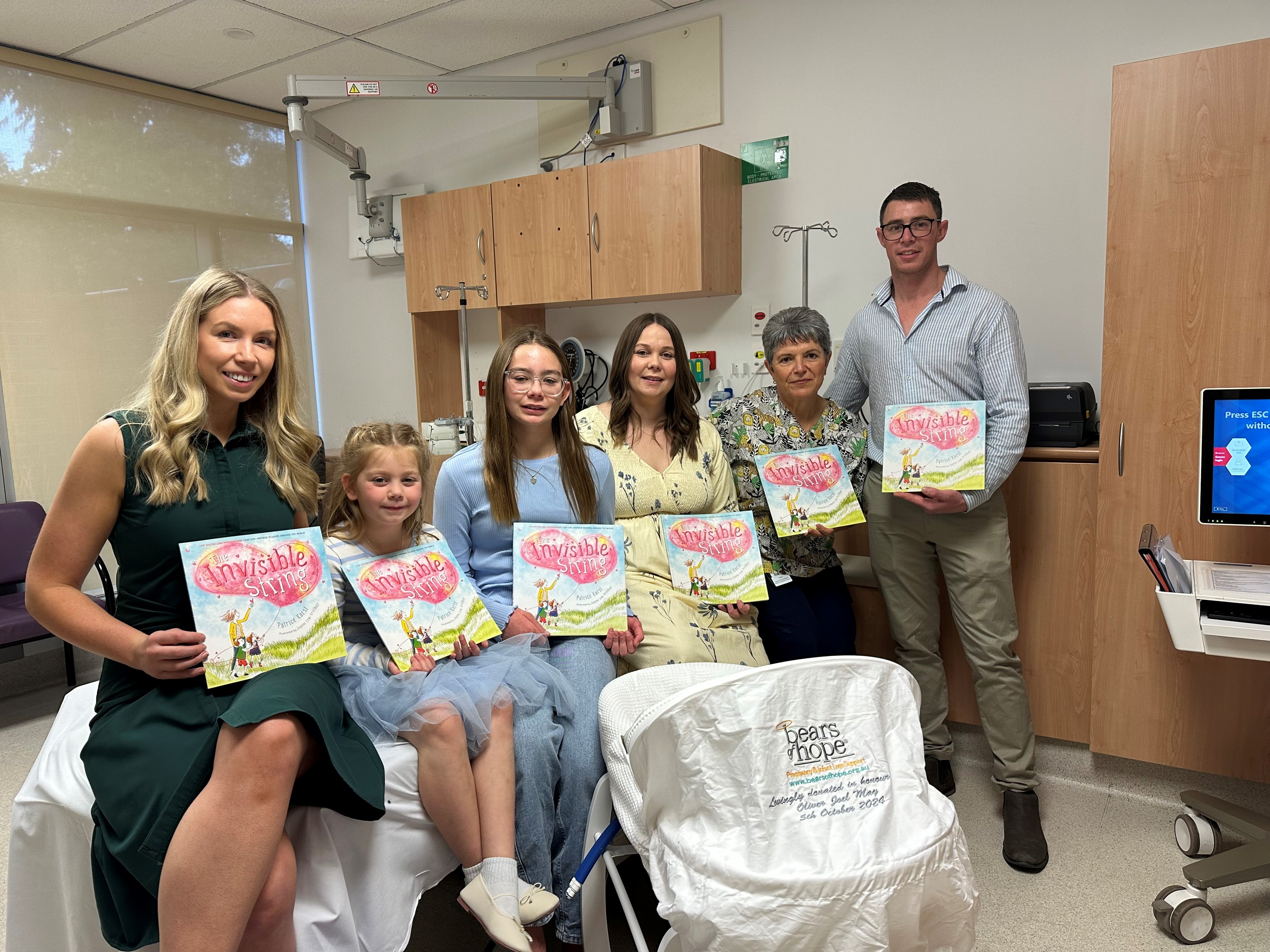 Parents Mikaela and Luke with daughters Amelia and Charlotte beside a Cuddle Cot in a hospital room.