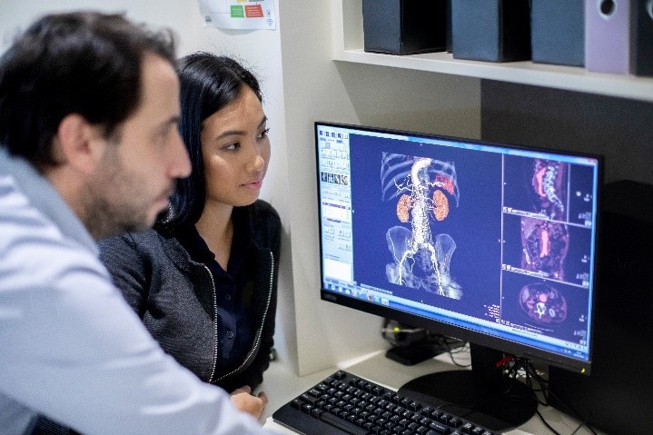 Clinicians reviewing medical imaging scans on a computer for diagnosis and monitoring.