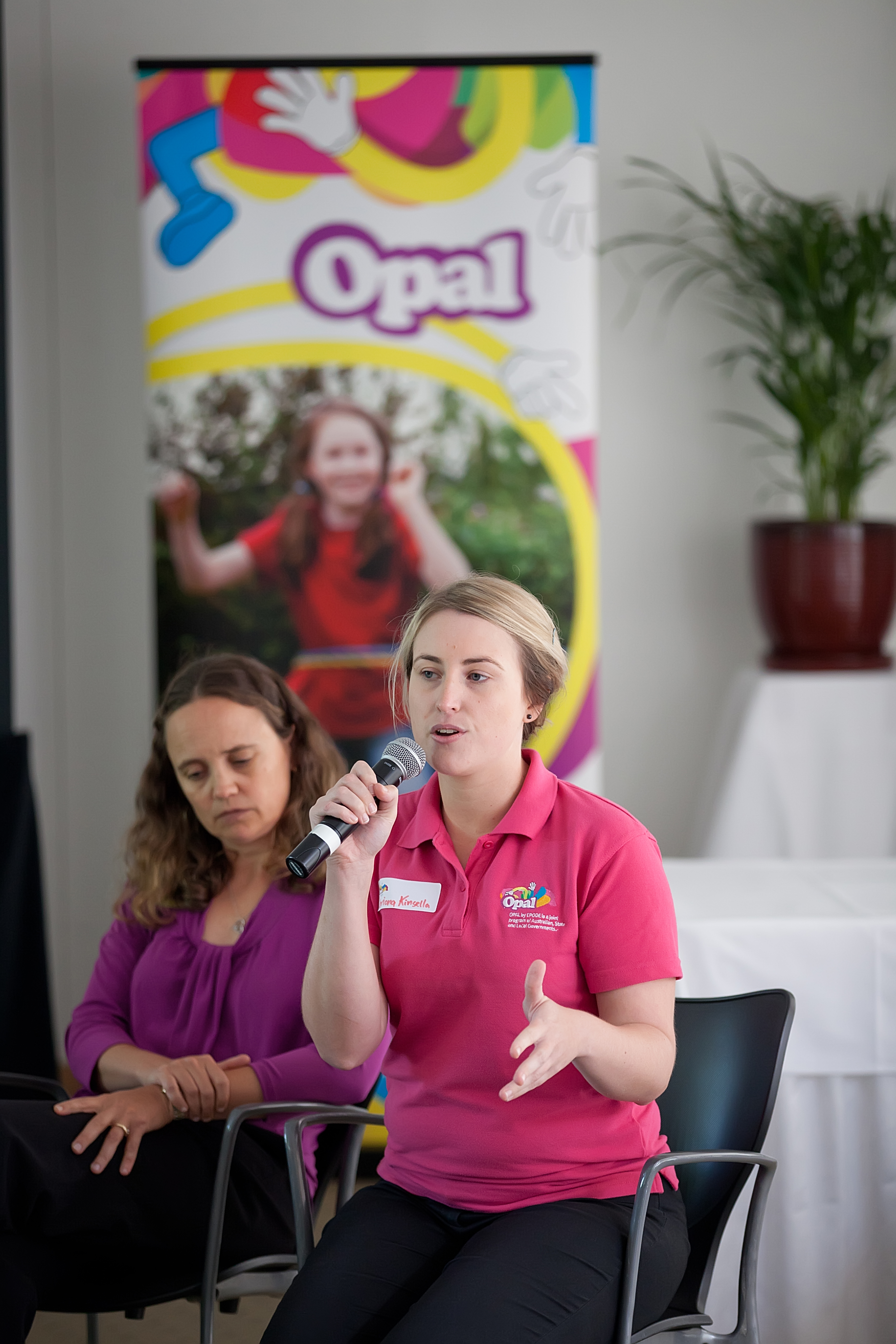 Female three speaking in front of OPAL banner