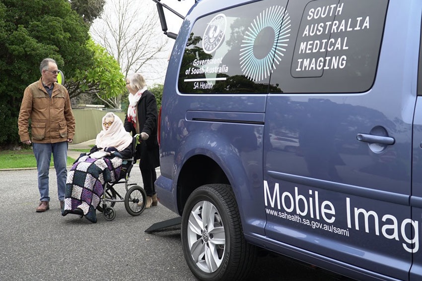 Elderly lady in wheelchair being assisted by two other people from the SAMI van