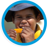Round photo with a blue border of a young boy eating a slice of orange